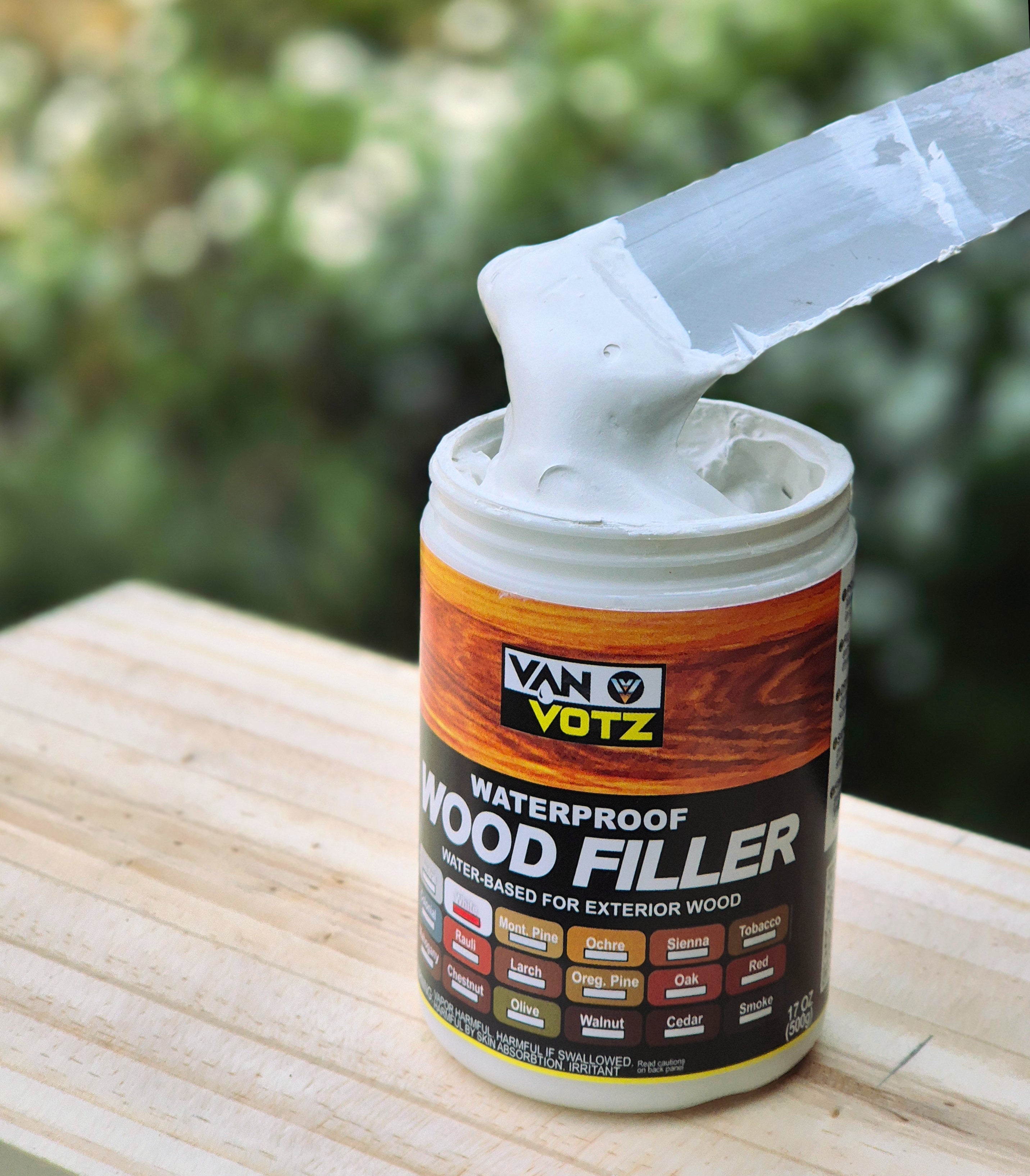 container of van votz waterproof wood filler spatula scooping up white paste showing texture and thickness
