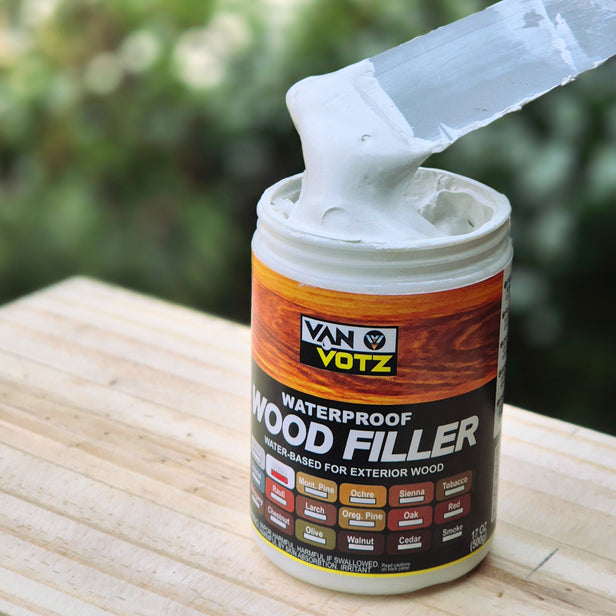 Van Votz waterproof wood filler can in white with a putty knife on a wooden surface